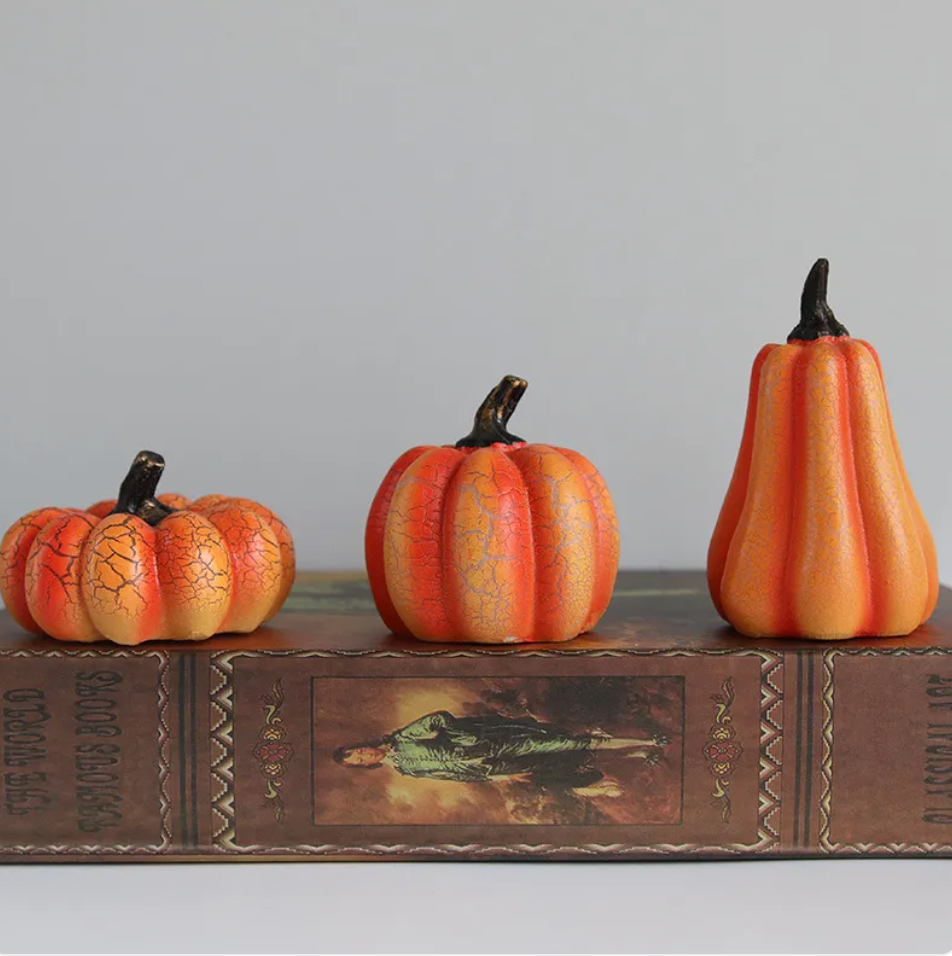 Three crackle-glazed resin pumpkins in graduated sizes lined up on a stack of vintage books