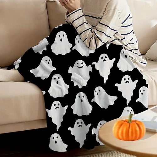 Person wrapped in the cute ghost flannel throw blanket on a cream sofa beside a pumpkin
