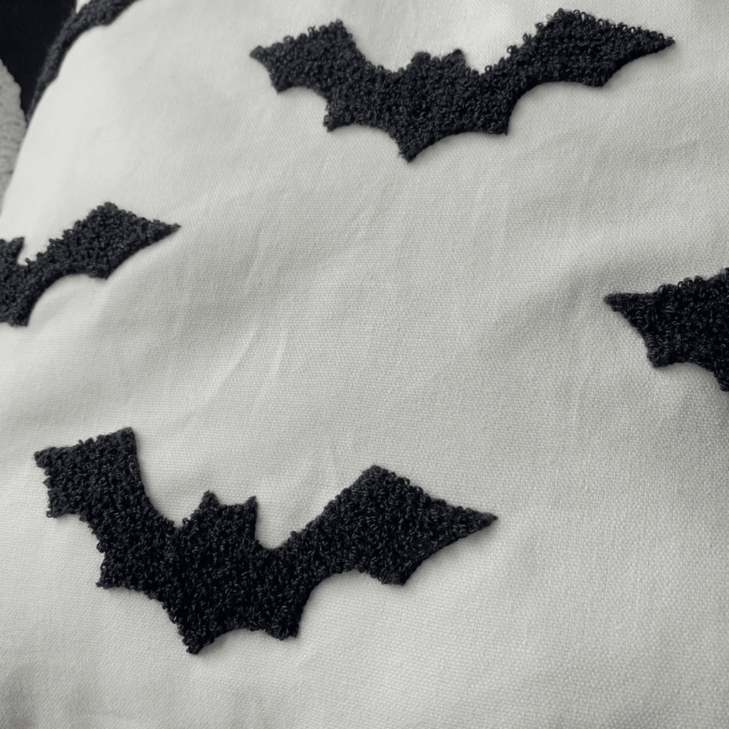 Close-up of black tufted bats on the cream pillow cover