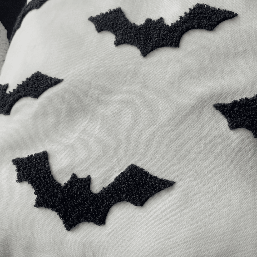 Close-up of black tufted bats on the cream pillow cover