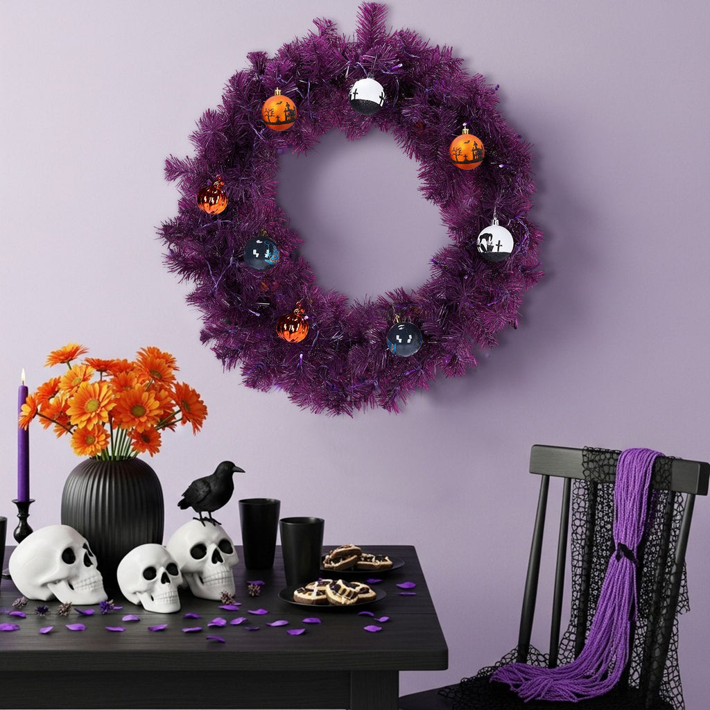 Purple Halloween wreath on a lilac wall above a table with orange flowers and skulls