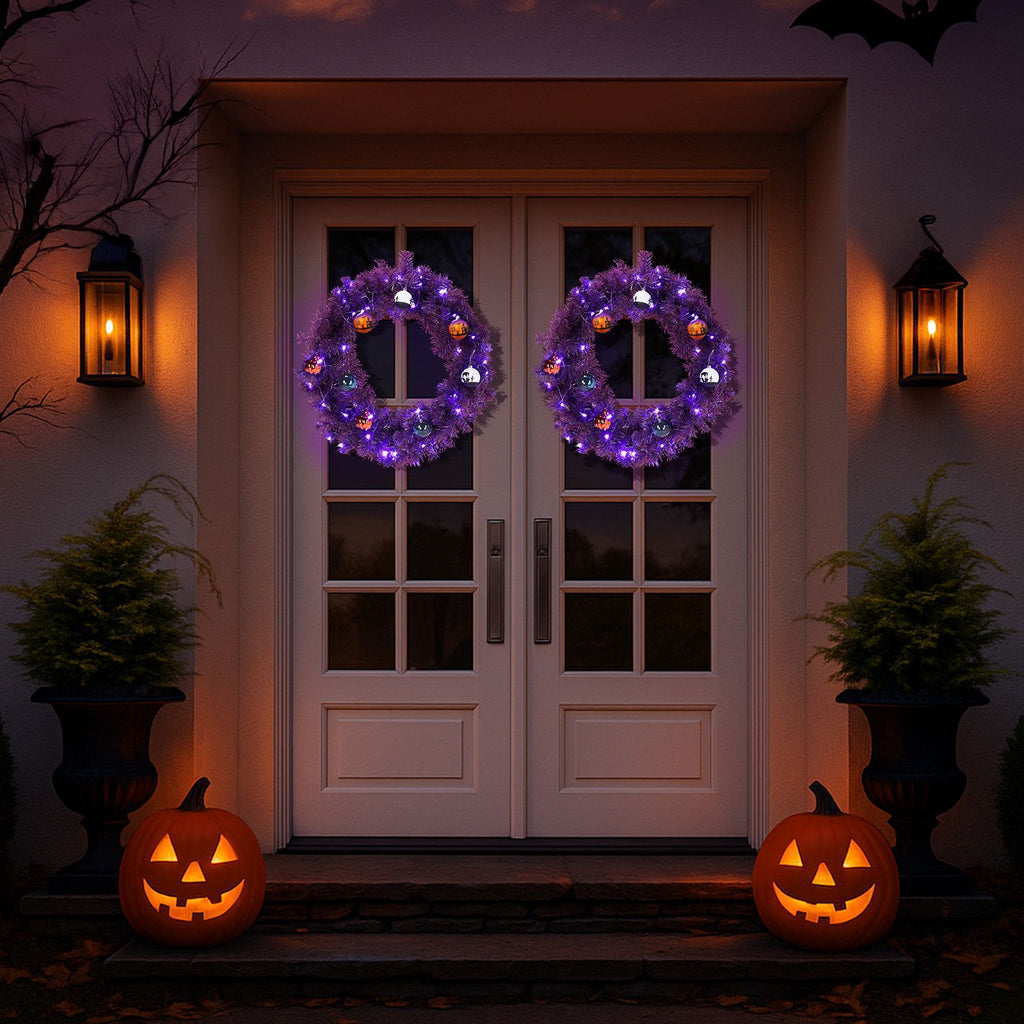 Two lit purple Halloween wreaths hung on a double front door at dusk with carved jack-o-lanterns on the step