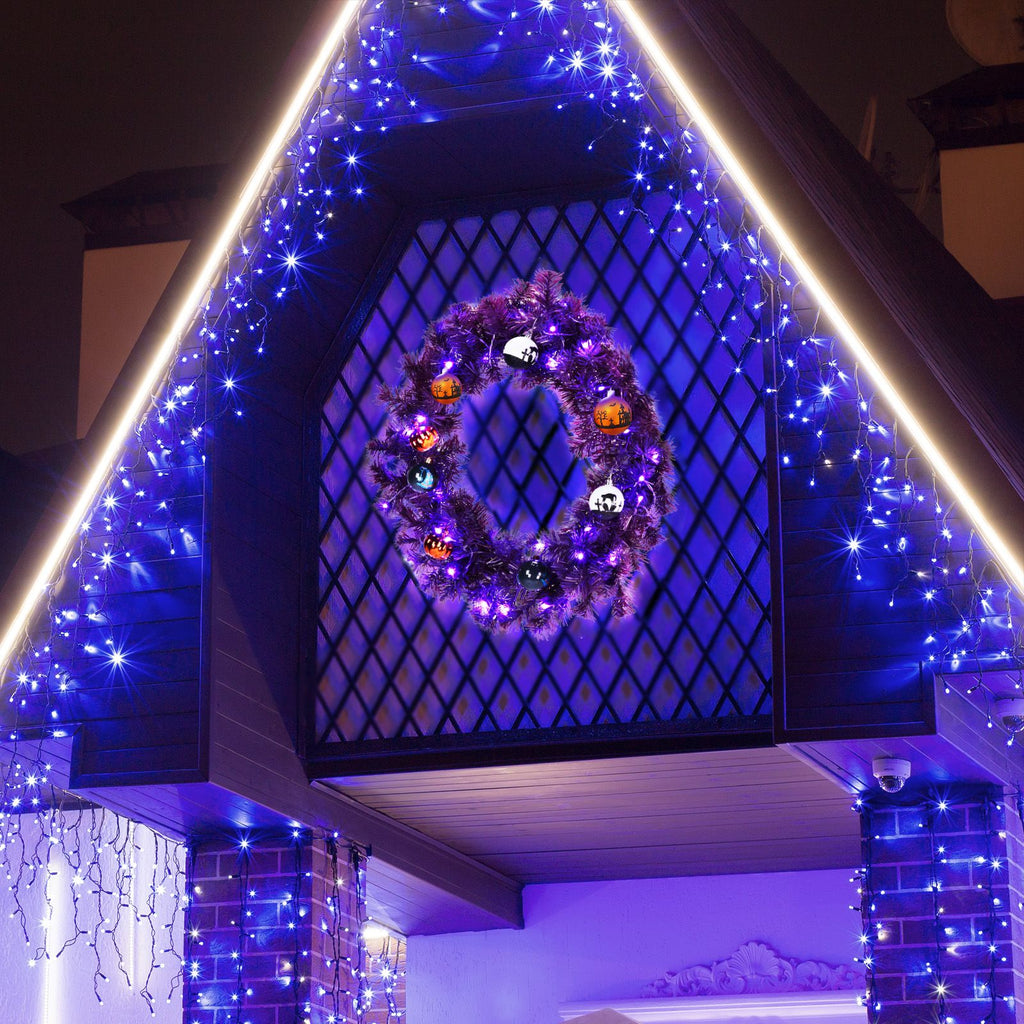Purple Halloween wreath lit on a covered porch beside blue string lights
