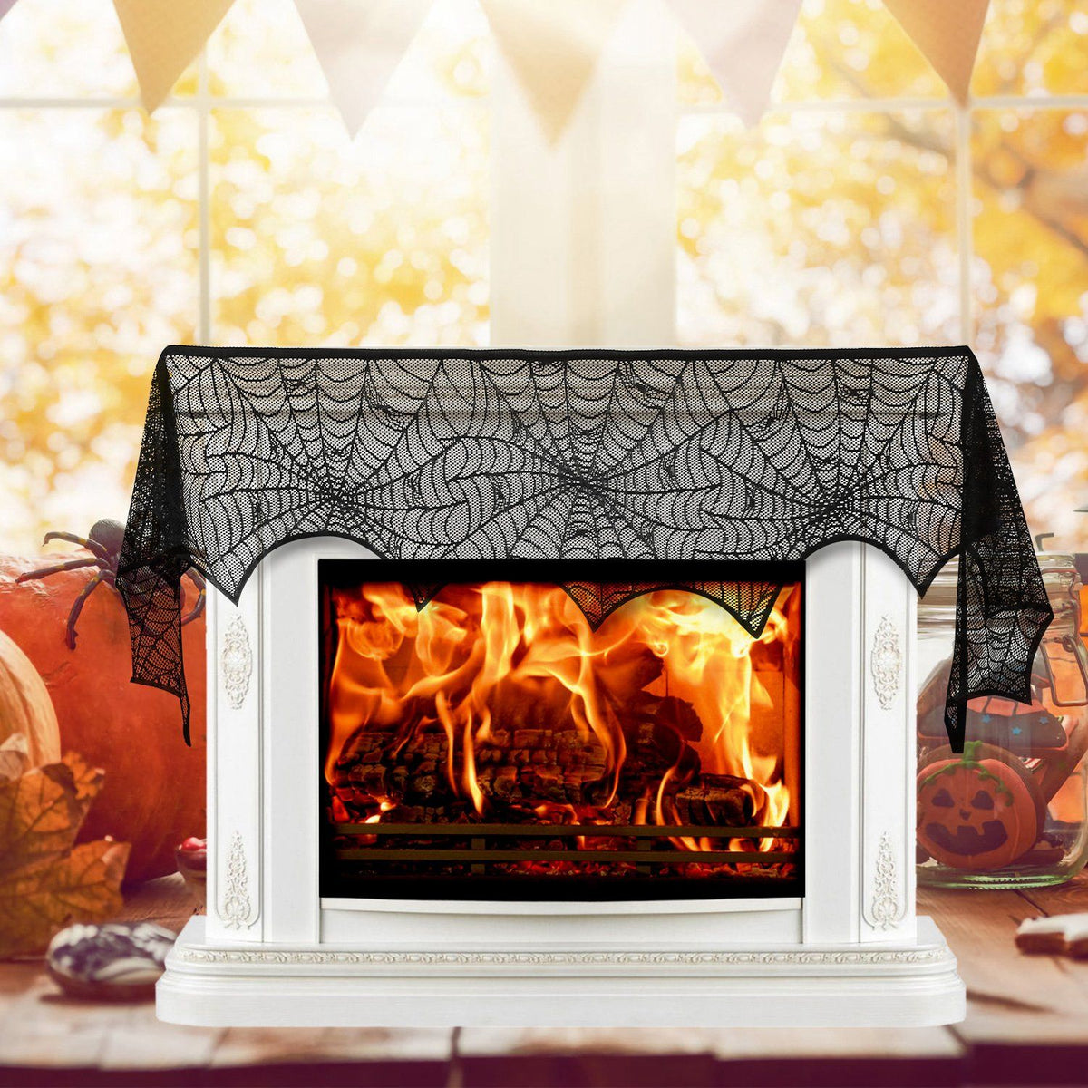 Black lace spiderweb mantel scarf draped over a white fireplace with a fire lit and pumpkins alongside