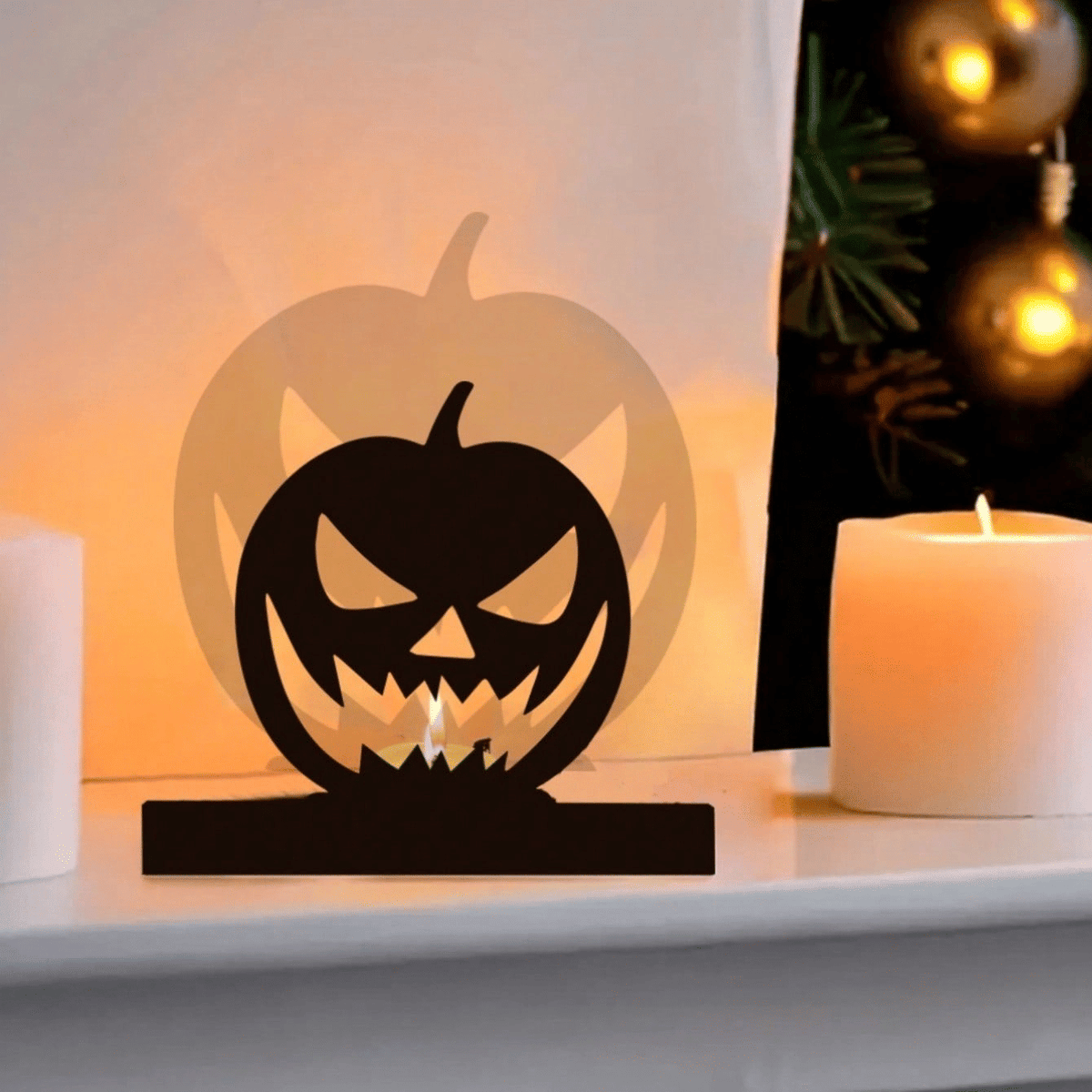 Jack-o'-lantern shadow tealight holder on a shelf beside a pillar candle and gold baubles