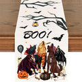 Cream linen Halloween table runner printed with four costumed dogs, bats, candy corn and a hand-lettered BOO