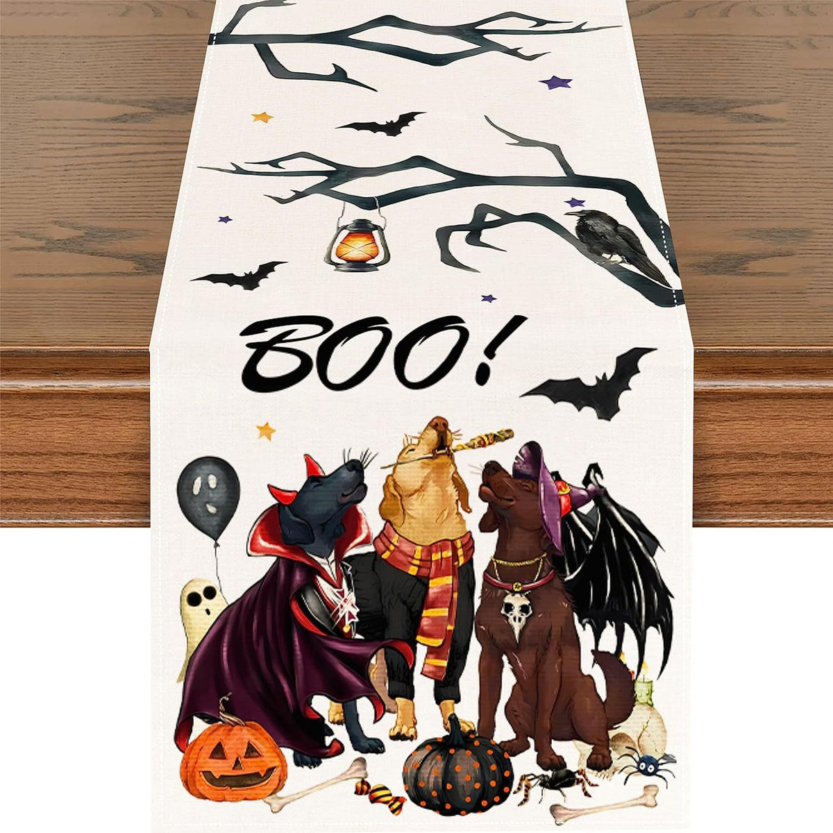 Cream linen Halloween table runner printed with four costumed dogs, bats, candy corn and a hand-lettered BOO