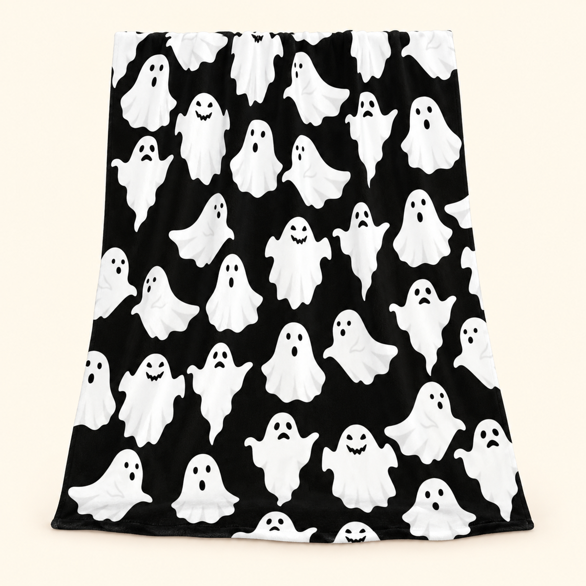 Black flannel throw blanket with white cartoon ghost print against a warm ivory background