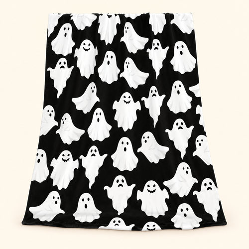 Black flannel throw blanket with white cartoon ghost print against a warm ivory background