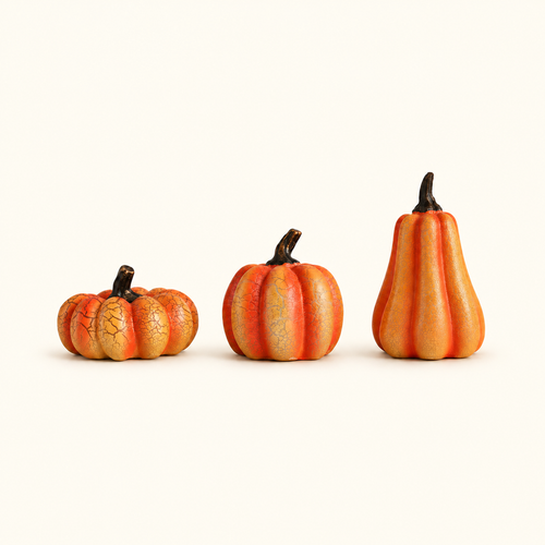 Set of three orange crackle-finish pumpkins in short, round and tall shapes on a warm ivory background